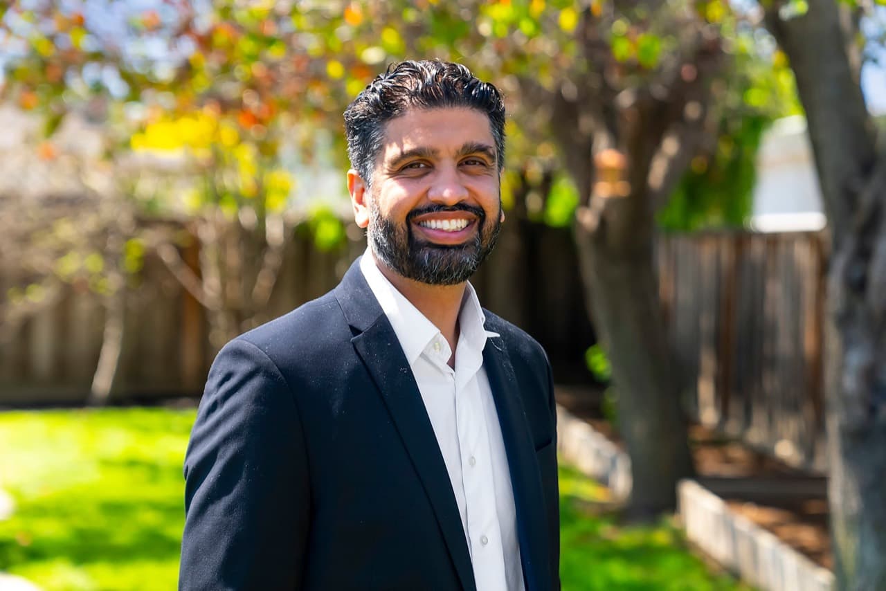 Portrait of Shug Sidhu standing outdoors in a dark suit